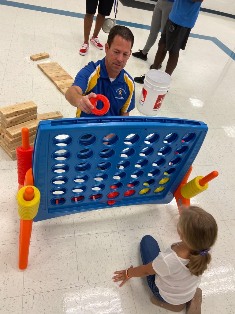 Staff member playing jumbo connect 4 with student